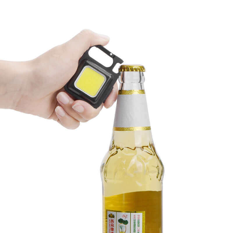 "Mini waterproof pocket torch LED keychain flashlight being used to open a bottle, showcasing its versatility and portable design."